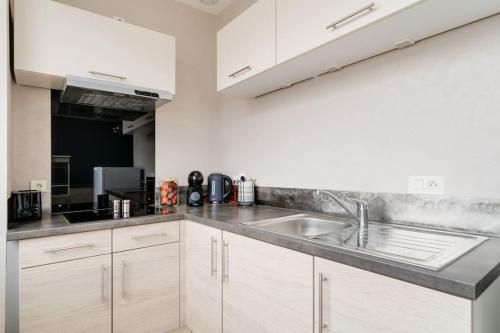 a kitchen with white cabinets and a sink at SUPERBE APPARTEMENT A UNE MINUTE A PIED DE LA GARE in Épinal