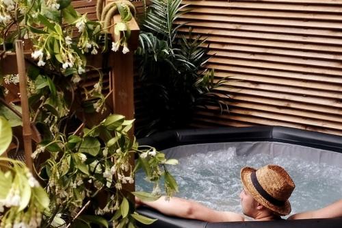 a person in a hot tub in a garden at Rez de maison/jacuzzi privé/patio fleuri in Olivese