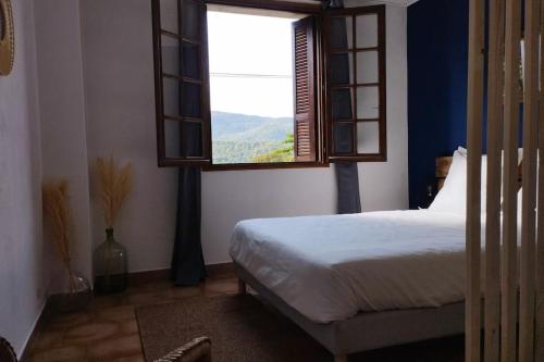 um quarto com uma cama e uma janela em Rez de maison/jacuzzi privé/patio fleuri em Olivese