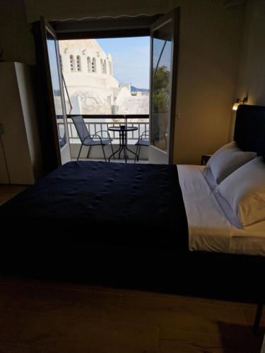 a bedroom with a bed and a balcony with a table at Above Apartments near the Airport in Artemida