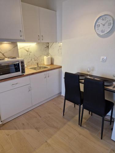 a kitchen with a table and two chairs and a microwave at Above Apartments near the Airport in Artemida