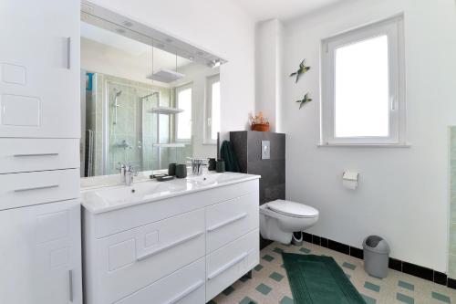 a white bathroom with a sink and a toilet at Le gîte de Vitazensel in Logelbach