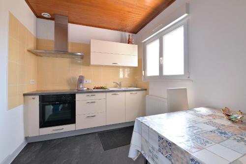 une cuisine avec des armoires blanches, un évier et une fenêtre dans l'établissement Le gîte de Vitazensel, à Logelbach