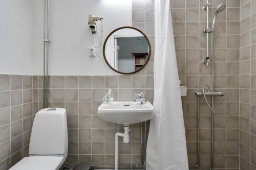 a bathroom with a toilet and a sink and a mirror at Hotell Hof in Askersund