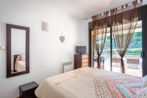 Un dormitorio con una cama y un espejo y una ventana. en Apartment Sa Boadella beach, Lloret de Mar - Costa Brava, en Lloret de Mar