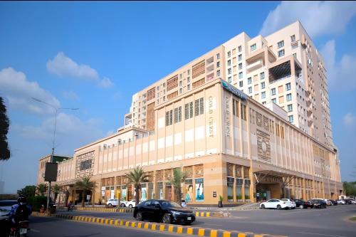 een groot wit gebouw in een stadsstraat met auto's bij Luxury 1 Bedroom Apartment Gold Crest Mall And Residency DHA in Lahore
