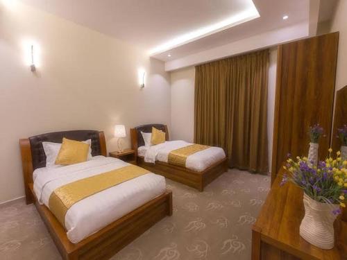 a hotel room with two beds and flowers in it at شاليه دوبلكس فالجونه للايجار in Hurghada