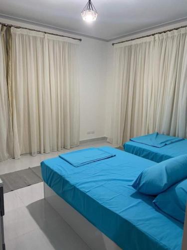 two blue beds in a room with curtains at شاليه دوبلكس فالجونه للايجار in Hurghada