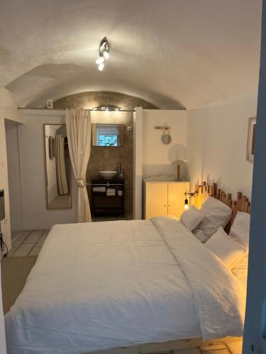 une chambre avec un grand lit blanc et une salle de bain dans l'établissement Maison du Vigneron, à Vézénobres