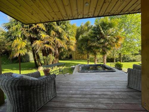 a wooden deck with chairs and a pool at chambre jacuzzi et jardin in Saint-Martin-de-Seignanx