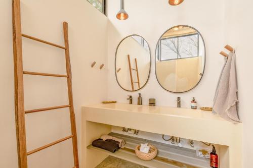 baño con lavabo y 2 espejos en Casa Arcilla NEW LISTING, en Nosara