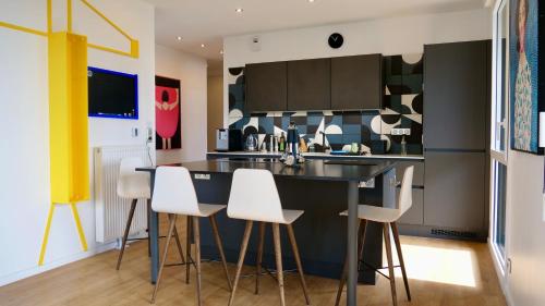 una cucina con bancone nero e sgabelli bianchi di Chambre D'hôtes sur Île de Nantes a Nantes
