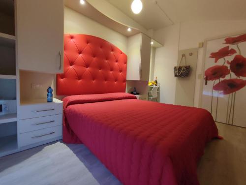 - un lit rouge avec une tête de lit rouge dans une chambre dans l'établissement Hotel Losanna Cervia, à Cervia