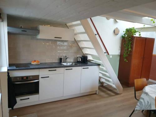 eine Küche mit weißen Schränken und einer Treppe in der Unterkunft La Casita Middelburg in Middelburg