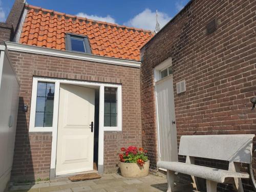 een stenen huis met een witte deur en een bank bij La Casita Middelburg in Middelburg