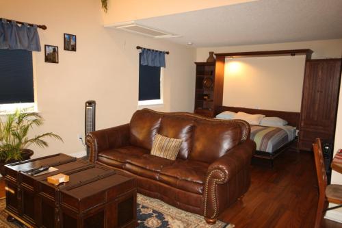 a living room with a leather couch and a bed at Woodrow House Bed & Breakfast in Lubbock