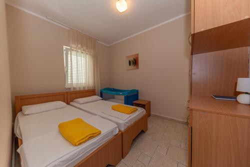 Cette petite chambre comprend 2 lits avec des draps jaunes. dans l'établissement Beach apartments, à Petrovac na Moru