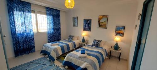 阿加迪爾的住宿－CASA ZOUINA，一间设有三张床的客房,配有蓝色和白色的床单