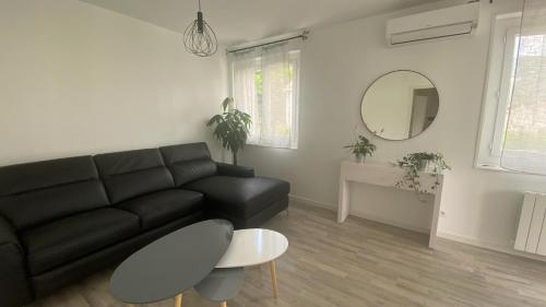 - un salon avec un canapé noir et un miroir dans l'établissement BEAUSOLEIL , appartement neuf, climatisé , Jardin clos , 2 chambres, parking privé, calme, 900 m du centre de nyons, à Nyons