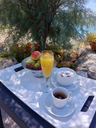 una mesa con un vaso de zumo de naranja y un bol de fruta en B&B Il Gabbiano, en Cittadella del Capo