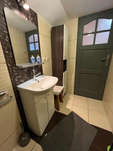 a bathroom with a sink and a black door at Domki Teo Piętrowe I Parterowe in Rewal