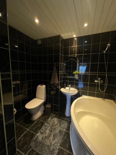 Baño de azulejos negros con aseo y lavamanos en Tallinn Street Apartment, en Kuressaare