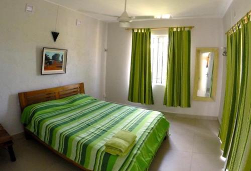 sypialnia z zielonym łóżkiem i zielonymi zasłonami w obiekcie Villas Hibiscus w mieście La Gaulette