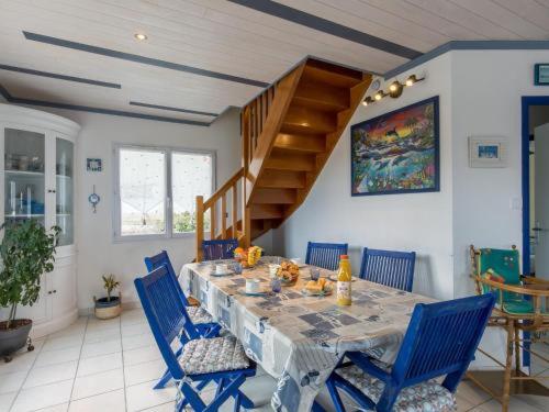 a dining room with a table and blue chairs at La Glycine in Lampaul-Plouarzel