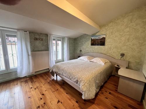 a bedroom with a bed and two windows at L’Ostalou in Issoire