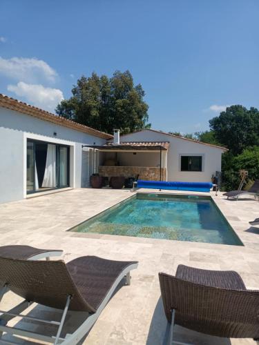 a swimming pool with chairs and a house at Villa au calme in Montauroux