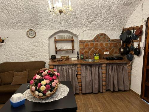 - un salon avec une table et un bol de fleurs dans l'établissement la cueva de guadix, à Guadix
