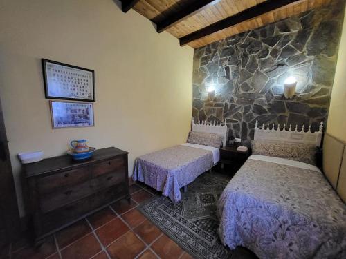 een slaapkamer met 2 bedden en een stenen muur bij La Buganvilla, descanso entre olivares in Hornachuelos