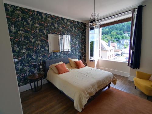 - une chambre avec un lit orné de papier peint floral et une fenêtre dans l'établissement La petite chouette, à Rochesson