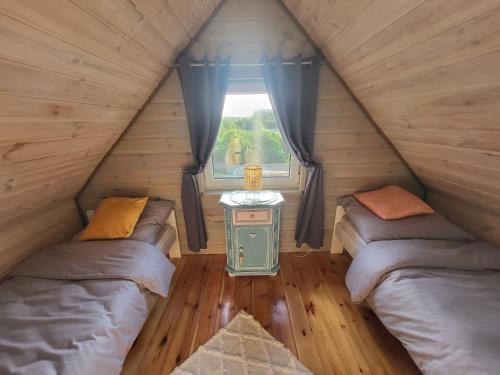 a attic room with two beds and a window at Przytulny domek w Brajnikach 86 37 in Jedwabno