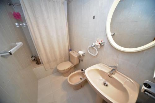 ein Badezimmer mit einem Waschbecken, einem WC und einem Spiegel in der Unterkunft CUMBREMAR Orangecosta in Benicàssim