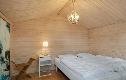 a bed in a wooden room with a lamp and a table at Lovely Home In Rnde With Kitchen in Rønde
