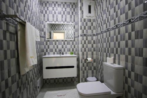 a bathroom with a toilet and a sink and a mirror at Hôtel Mansour in Dakhla