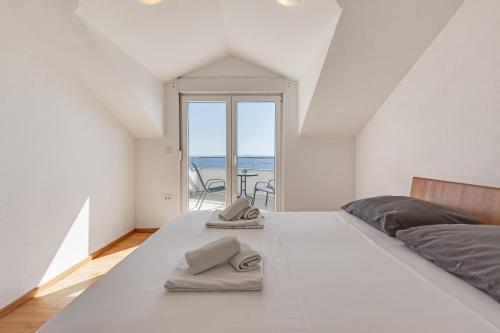 a bedroom with a large white bed with a view of the ocean at Villa Mirela in Petrcane