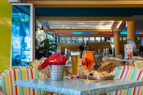 a table with a glass of beer and some chairs at Hotel Ettoral in Lido di Jesolo