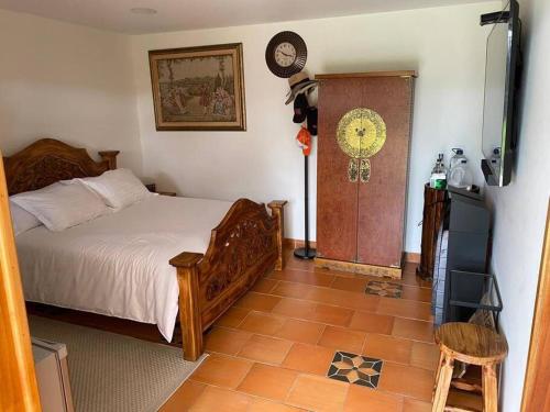 1 dormitorio con 1 cama y reloj en la pared en Linda Casa Colonial Remodelada, en Guasca