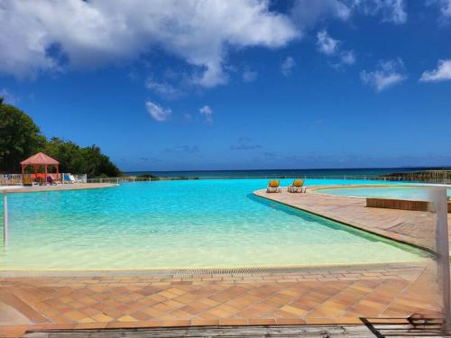 ein Pool mit blauem Wasser und einigen Stühlen in der Unterkunft studio colibri in Saint-François