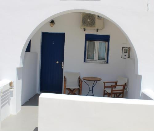 a room with a blue door and a table and chairs at Meltemi Rooms and Studios in Anafi