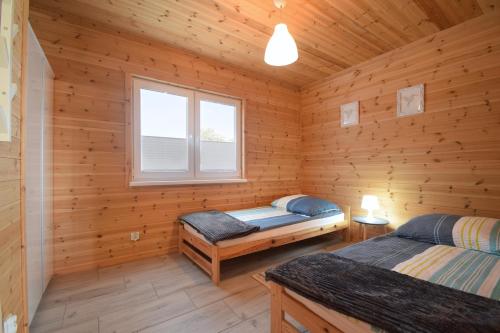 a log cabin with two beds and a window at Kalimera in Sarbinowo