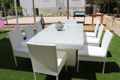 a white table with white chairs and a vase on it at Can Mossènyer in San Antonio