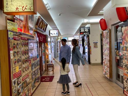a man and a woman and a child in a store at Tokyu Stay Hakodate Asaichi Akarinoyu in Hakodate