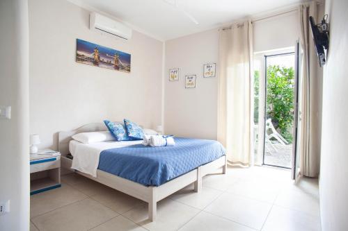 a bedroom with a bed with blue sheets and a window at B&B Peonies in Castellammare di Stabia