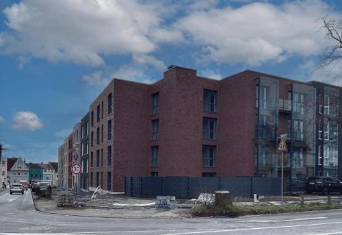 un edificio di mattoni rossi sul lato di una strada di Moderne Wohnung mit Loggia - Neubau 2023 a Bergisch Gladbach