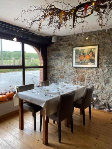 una sala da pranzo con tavolo e parete in pietra di La Trouvaille a Waimes