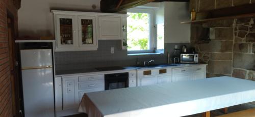 - une cuisine avec des placards blancs et un mur en pierre dans l'établissement Gite de la Ville aux Bois, à Parigné