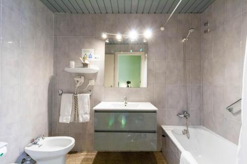 a bathroom with a sink and a tub and a toilet at Hotel Castell Blanc in Empuriabrava